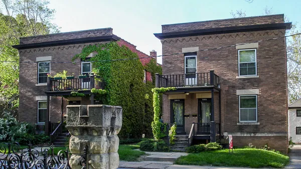 Side-by-side brick duplexes pictured on a sunny day.